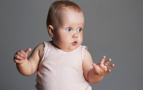 Удивленный маленький ребенок на сером фоне