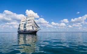 Большой корабль с белыми парусами в море под голубым небом
