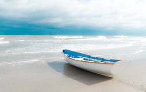 Лодка стоит на белом песке у моря 