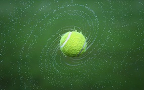 Tennis ball in splashing water on green background