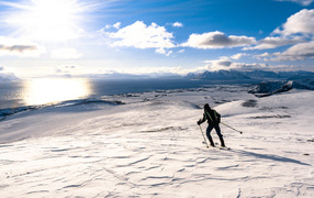 Лыжник едет по снегу под ярким солнцем у воды