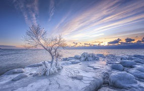 Обледеневшие камни на берегу озера на закате зимой