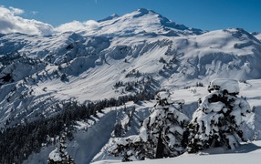 Заснеженные склоны гор в лучах солнца под голубым небом 