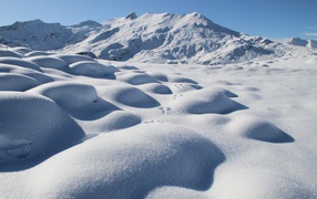 Заснеженные камни на поверхности горы в лучах солнца