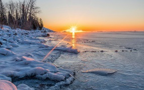 Яркое солнце освещает покрытые снегом берега реки 