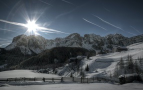 Яркое зимнее солнце встает из -за заснеженных гор 