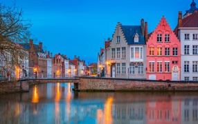 Большие дома и фонари отражаются в воде канала вечером