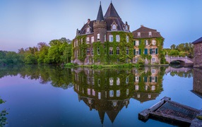 The ancient green-covered castle of Linnep is reflected in the water