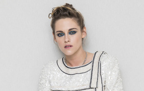 Actress Kristen Stewart with painted eyes against a gray wall