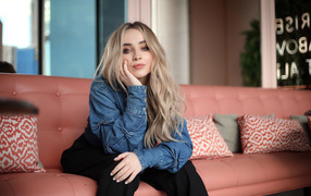 Актриса Сабрина Карпентер сидит на диване в комнате