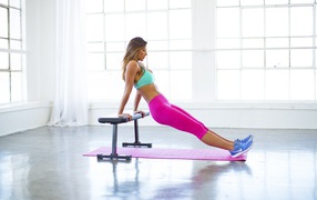 Спортивная девушка в розовых лосинах в спортзале 