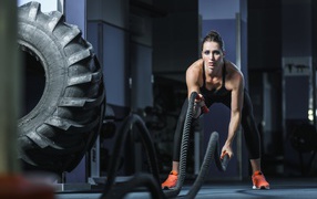 Спортивная девушка занимается с канатами в спортзале 