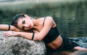 Красивая девушка в черном наряде с татуировками на руках 