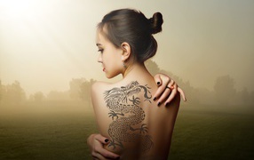 Красивая девушка с татуировкой дракона на спине
