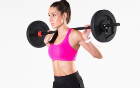 Красивая спортивная девушка со штангой на белом фоне