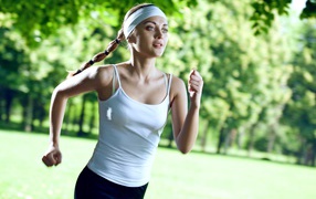Девушка спортсменка в белой майке занимается бегом