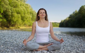 Girl in lotus position meditates by the river
