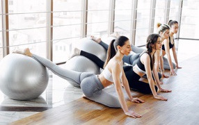Девушки делают упражнения с фитболом в спортзале