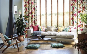 Серый мягкий диван стоит у большого окна в комнате