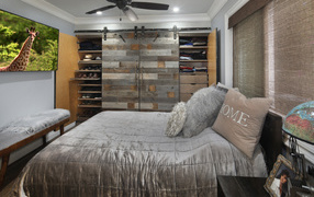 Large gray bed in the bedroom with wooden interior