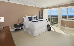 Large high bed in a spacious bedroom with a guitar