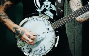 Мужчина с татуировками на руках с гитарой