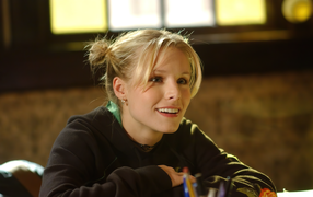 Улыбающаяся актриса Кристен Белл сидит в классе 