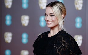 Улыбающаяся актриса Марго Робби в черном платье 