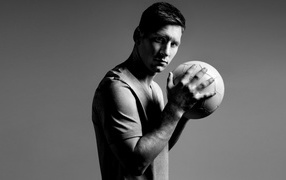 Soccer player Lionel Messi with a ball in his hands on a gray background