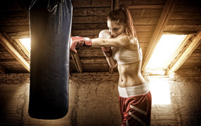 Sports girl beats a punching bag
