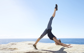 Спортивная девушка делает упражнения на берегу моря 