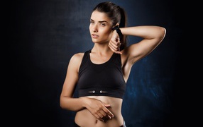 Спортивная девушка в черном костюме с часами на руке