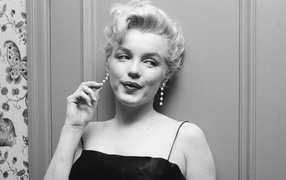 The legendary Marilyn Monroe stands against the wall, black and white photo