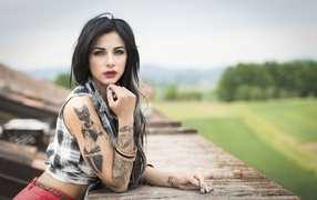 Молодая девушка брюнетка с татуировками на руках