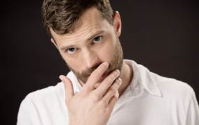 Молодой мужчина, актер Джейми Дорнан с рукой у лица