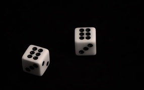 Две белые игральные кости с шестерками на черном фоне