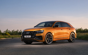 Оранжевый автомобиль Audi SQ8 TFSI 2021 года на фоне неба