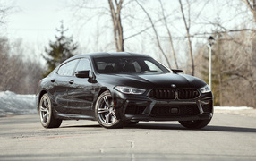 Черный автомобиль BMW M8 в лучах солнца