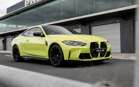 Желтый автомобиль BMW M4 Competition 2021 года у здания