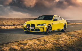 Yellow 2021 BMW M4 Competition car against a stormy sky