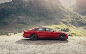 Красный автомобиль Bentley Flying Spur V8 2020 года у горы 