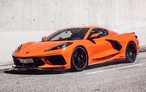 Оранжевый Chevrolet Corvette 2021 года на фоне серой стены