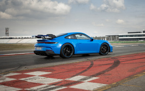 Голубой автомобиль  Porsche 911 GT3 2021 года на трассе