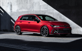 Red 2021 Volkswagen Golf GTI car against a gray wall