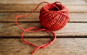 Клубок красной пряжи на деревянном столе 