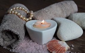 Красивая свеча с полотенцем, бусами, камнями и морской солью