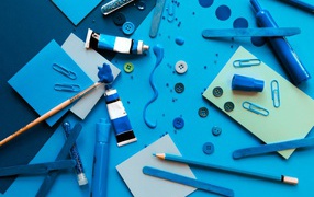 Синие канцелярские предметы, бумага и краски на столе 