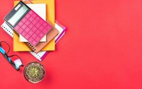 Калькулятор с очками и блокнотами на розовом фоне 