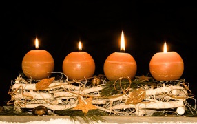 Четыре круглые зажженные свечи на черном фоне