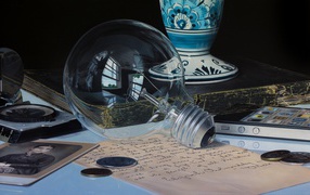 Стеклянная лампочка на столе с монетами и письмом